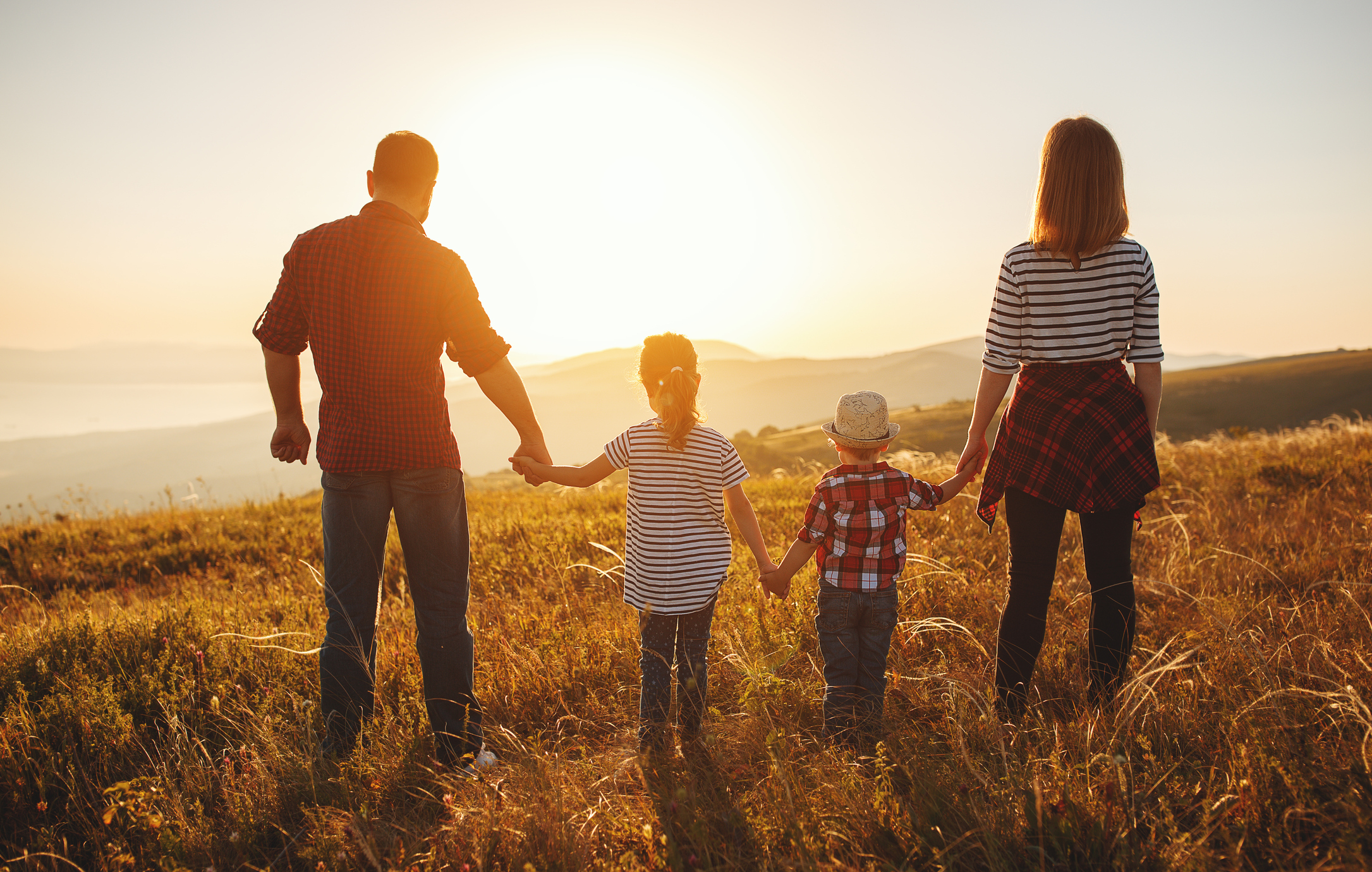 Mother, father, son and daughter in nature in front of a sunset